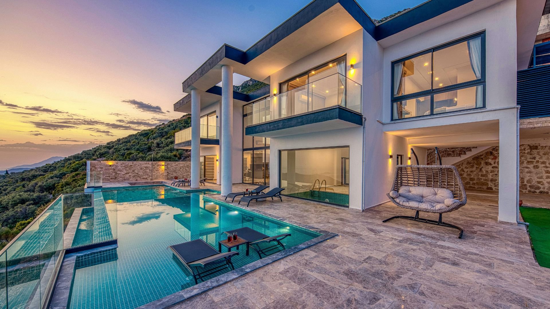 Luxurious modern villa with infinity pool overlooking mountainous landscape at sunset