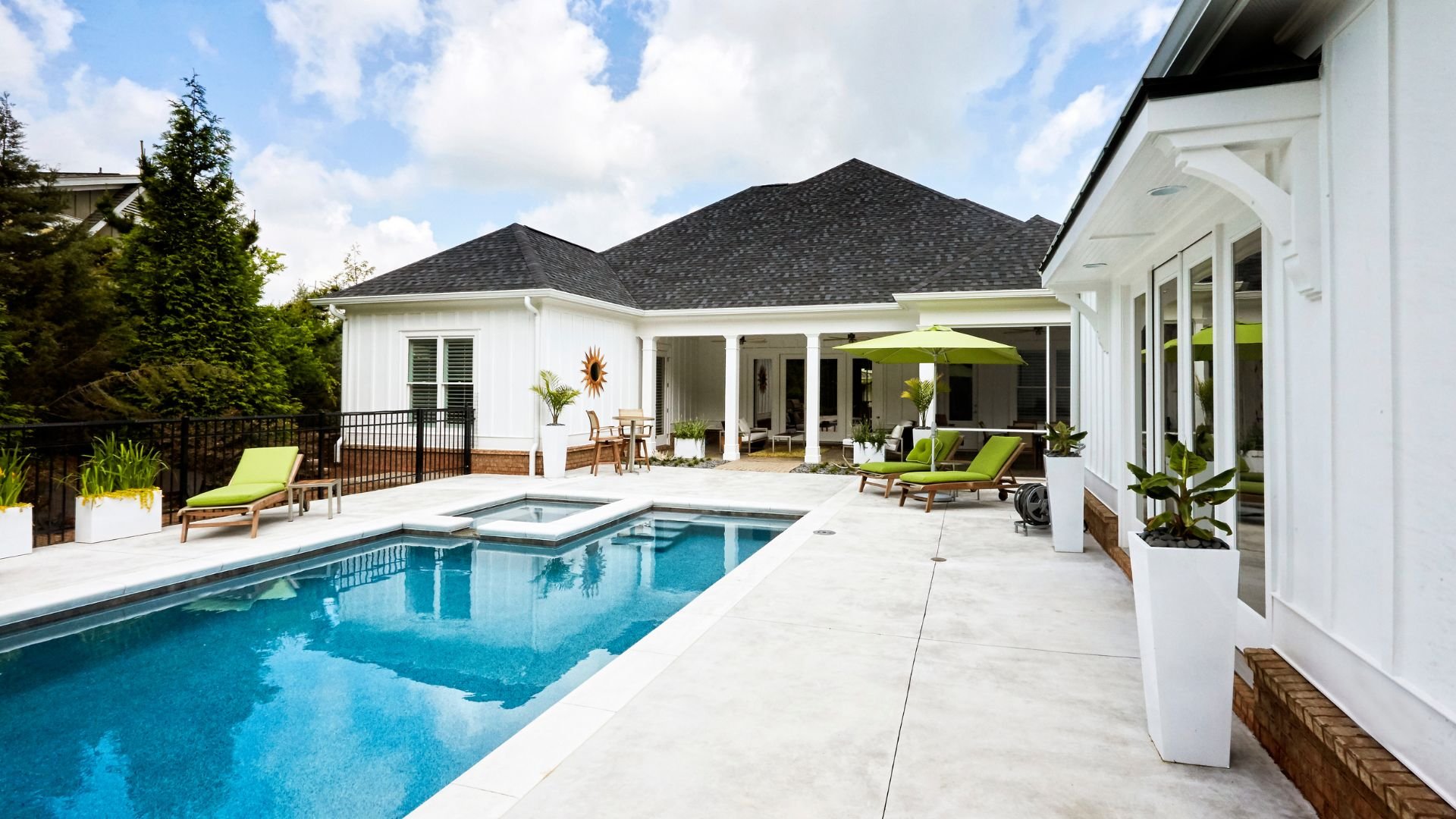 Luxurious white house with swimming pool, green loungers, and covered patio